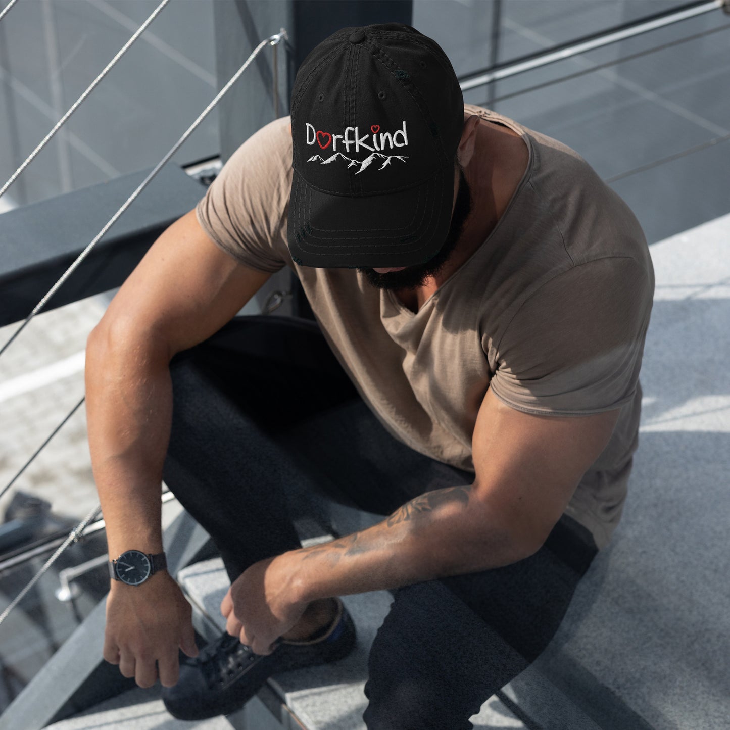 Mann trägt einen schwarzen Dad-Hat im Used-Look mit "Dorfkind" und Bergmotiv.