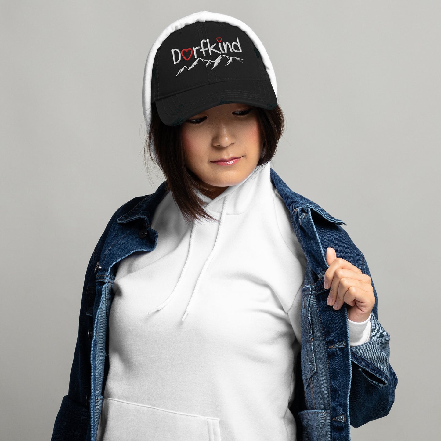 Frau trägt einen schwarzen Dad-Hat im Used-Look mit "Dorfkind" und Bergmotiv.