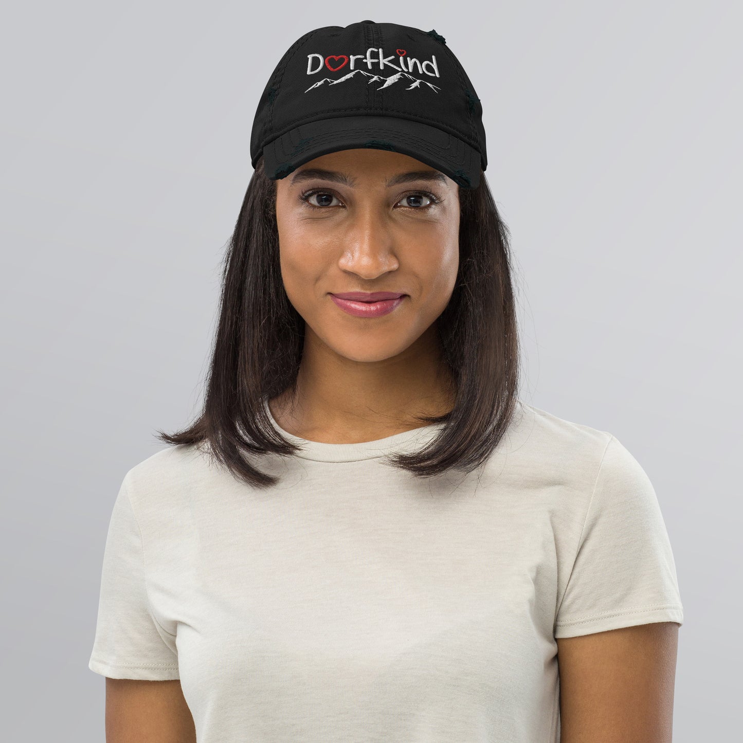 Frau trägt einen schwarzen Dad-Hat im Used-Look mit "Dorfkind" und Bergmotiv.