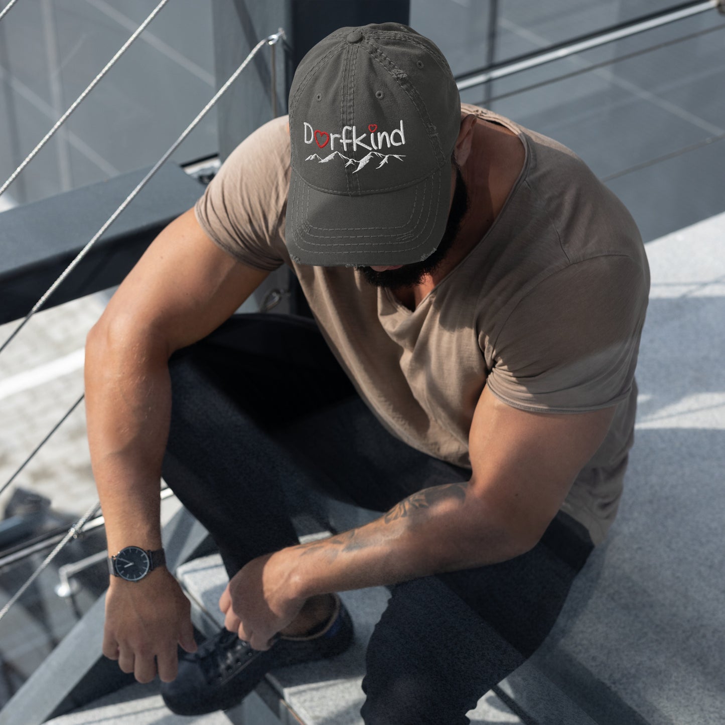Mann trägt einen schwarzen Dad-Hat im Used-Look mit "Dorfkind" und Bergmotiv.